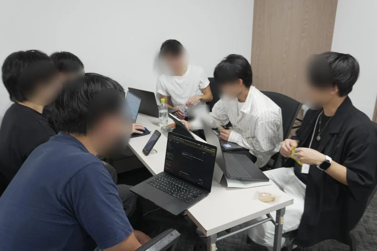 ノートパソコンを囲んでグループワークに取り組むチーム