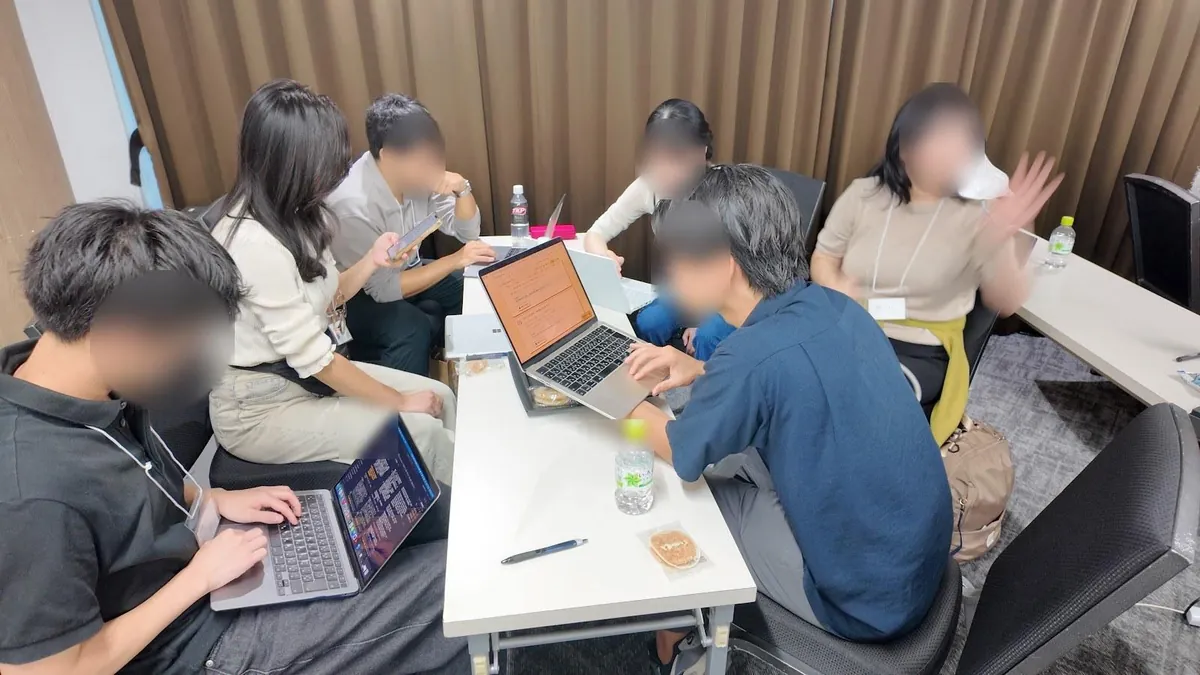 机を囲んで話し合いながら作業するチーム